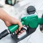 A worker holds a nozzle to pump petrol into a vehicle at a fuel station.