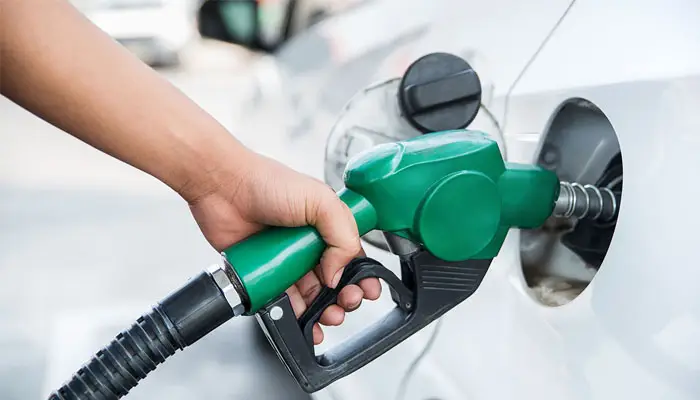 A worker holds a nozzle to pump petrol into a vehicle at a fuel station.